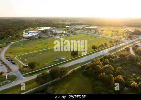 Beleuchtete öffentliche Sportarena in North Port, Florida, wo die Leute bei Sonnenuntergang im Grasfußballstadion Fußball spielen. Konzept für Outdoor-Aktivitäten Stockfoto