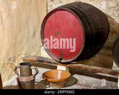 Ein alter Weinkeller in einem typisch spanischen Landhaus. Es gibt ein großes Holzfass und einige Werkzeuge und Utensilien, um Wein zu machen. Stockfoto