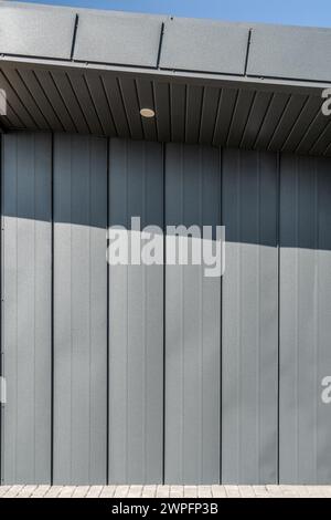 Modernes Gästehaus mit schwarzer Metallfassade. Minimalistisches Außendesign in der Stadt an sonnigen Tagen. Wandpaneele aus Stahl Stockfoto