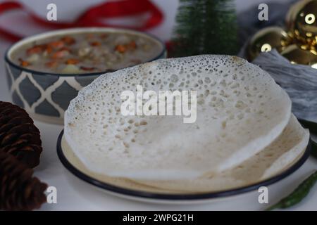 Ein traditionelles Kerala-Frühstück mit Appam und Eintopf. Appam ist ein weicher und flauschiger Pfannkuchen aus Reismehl und Kokosmilch. Eintopf ist cremig und würzig Stockfoto