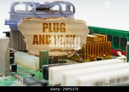 Auf der Hauptplatine des Computers befindet sich ein Karton mit der Aufschrift „Plug and Play“. Computerkonzept. Stockfoto