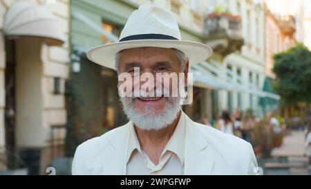 Lächelnd glücklich lachend alter älterer älterer älterer, reifer, grauhaariger, eleganter Geschäftsmann, männlicher, touristischer Reisender, der die Kamera positiv betrachtet Stockfoto