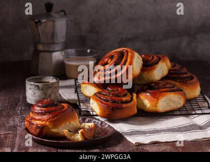 Hefeteig mit Zimt mit Mohnsamen, Rosinen und kandierten Früchten, serviert mit Kaffee. Rustikaler Stil. Stockfoto
