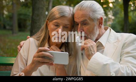 Verwirrtes besorgtes kaukasisches altes Seniorenpaar pensionierte Familie älterer Mann Frau, die Smartphone sucht schlechte Nachrichten Benachrichtigung erhält negative Reaktion Stockfoto