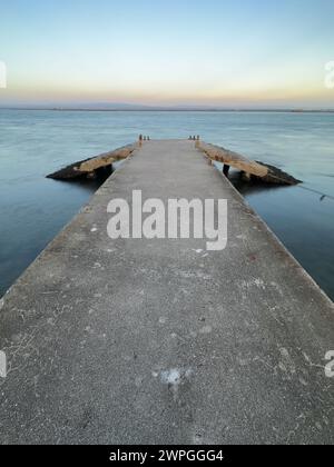 Leerer Betonpier zur Ria de Aveiro in Portugal mit dramatischem Himmel und ruhigem Wasser. Stockfoto