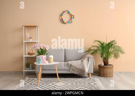Inneneinrichtung des modernen Wohnzimmers mit Blumen, Häschen und Osterkuchen auf Couchtisch Stockfoto