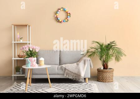 Inneneinrichtung des modernen Wohnzimmers mit Blumen, Häschen und Osterkuchen auf Couchtisch Stockfoto