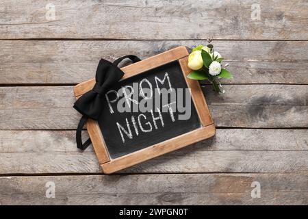 Tafel mit Text ABSCHLUSSBALL NACHT, Fliege und Boutonniere auf hölzernem Hintergrund Stockfoto