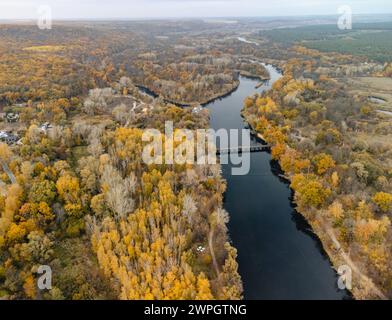 Luftaufnahme auf der Brücke über den Fluss mit gelben Herbstbäumen und Erholungsgebiet in Korobovy Hutora (Dorf Koropove) in der Ukraine Stockfoto