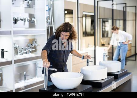 Ein Mann inspiziert und wählt einen neuen Küchen- oder Badezapfhahn im Baumarkt aus Stockfoto