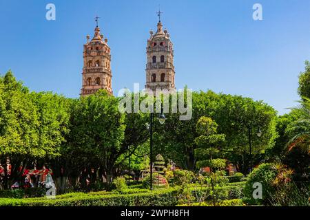 Die zwei Glockentürme der Pfarrkirche Nuestra Señora de la Luz oder der Kirche unserer Lieben Frau vom Licht, die über den Jardin de Salvatierra Park im zentralen historischen Viertel von Salvatierra, Guanajuato, Mexiko, gesehen wird. Die neogotische Kirche aus dem 17. Jahrhundert ehrt die Patronin der Stadt. Stockfoto