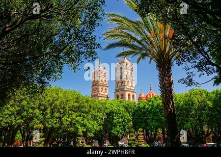 Die zwei Glockentürme der Pfarrkirche Nuestra Señora de la Luz oder der Kirche unserer Lieben Frau vom Licht, die über den Jardin de Salvatierra Park im zentralen historischen Viertel von Salvatierra, Guanajuato, Mexiko, gesehen wird. Die neogotische Kirche aus dem 17. Jahrhundert ehrt die Patronin der Stadt. Stockfoto