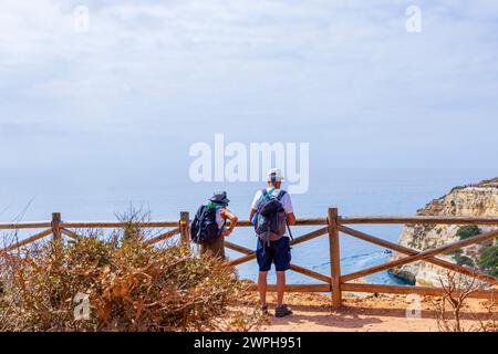Ein paar Touristen mittleren Alters mit Rucksäcken, die den Blick auf das Meer von oben genießen. Benagil, Carvoeiro, Algarve, Portugal. Stockfoto