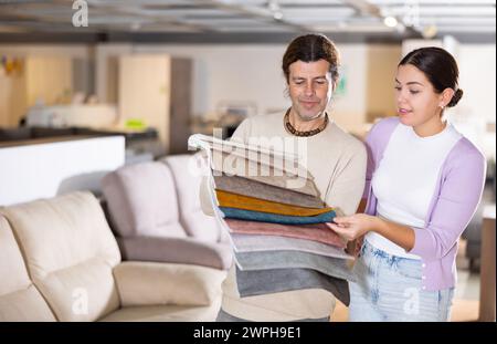 Der Mann präsentiert einer Frau Polstermuster Stockfoto