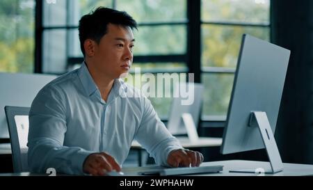 Konzentrierter reifer asiatischer japanischer koreanischer Mann Büroangestellter professioneller Geschäftsmann Unternehmer Arbeit in der Geschäftsfirma Computerspiel entwickeln Stockfoto