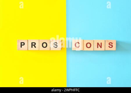 Vor- und Nachteile-Konzept. Holzblöcke Typografie auf hellblauem und gelbem Hintergrund. Stockfoto