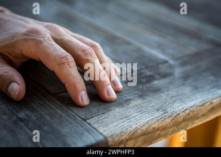 Die Hand eines Mannes ruht auf einem Holztisch Stockfoto