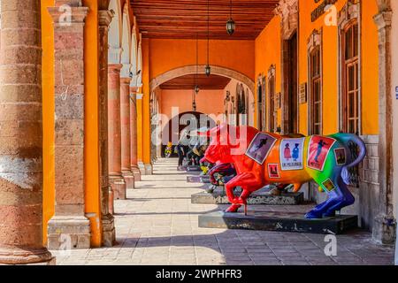 Individuell bemalte Statuen von Stieren säumen die Portales del Carmen entlang des zentralen historischen Viertels in Salvatierra, Guanajuato, Mexiko. Stockfoto