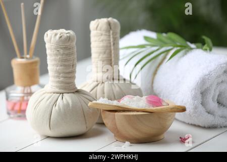 Wunderschöne Spa-Komposition mit Kräutertüten, Meersalz und Schilflufterfrischer auf weißem Holztisch, Nahaufnahme Stockfoto