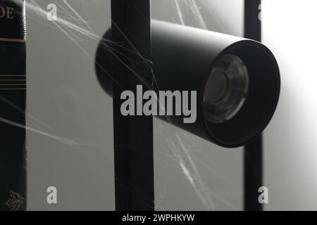 Spinnweben auf Lampe vor grauem Hintergrund, Nahaufnahme Stockfoto