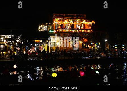 Mit Laternen beleuchtete Holzboote nehmen Einheimische und Touristen mit auf einen Ausflug auf dem Fluss Thu Bon in der Altstadt von Hoi an, Vietnam. Stockfoto