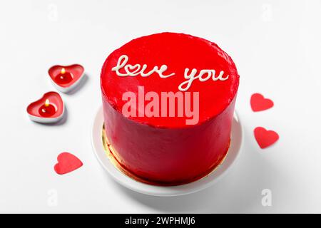 Bento Kuchen mit Text Love You, Kerzen und Papierherzen auf weißem Tisch. St. Valentinstag-Überraschung Stockfoto
