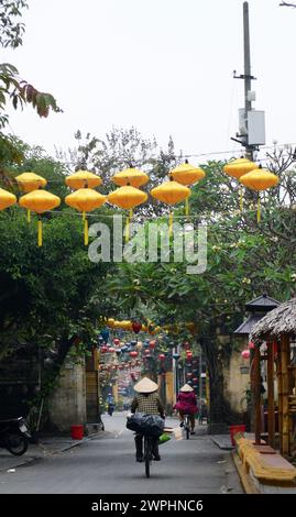 Eine vietnamesische Frau radelt in der Altstadt von Hoi an, Vietnam. Stockfoto