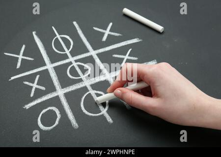 Frau spielt Tic Tac Toe auf Tafel, Nahaufnahme Stockfoto