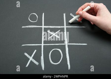 Frau spielt Tic Tac Toe auf Tafel, Nahaufnahme Stockfoto