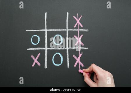 Frau spielt Tic Tac Toe auf Tafel, Nahaufnahme Stockfoto