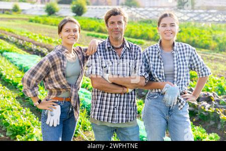 Porträt von drei glücklichen Bauern vor dem Hintergrund eines Feldes mit Gemüseernte Stockfoto