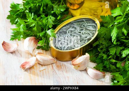 Eingelegte Aale in offener Dose mit Knoblauch am Tisch Stockfoto