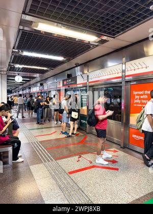 Pendler warten auf das Einsteigen an der City Hall Station auf dem Singapore Mass Rapid Transit System Stockfoto