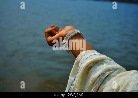 Frauen tragen silberne Armreifen im Handgelenk, die sich Richtung Fluss zeigen. Stockfoto
