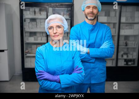 Gesundheitspersonal in blauen Uniformen stehen im Labor Stockfoto