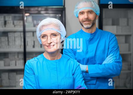 Laborassistenten in blauen Uniformen stehen im Labor Stockfoto