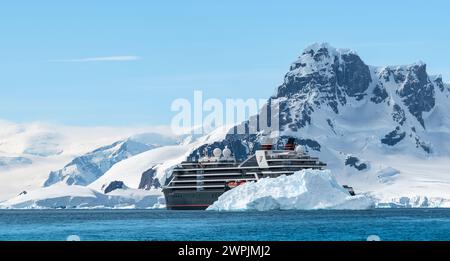 Hanusse Bay, Antarktis - 14. Januar 2024: Kreuzfahrtschiff Seabourn Pursuit hinter Eisberg in der Antarktis. Stockfoto