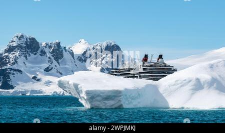 Hanusse Bay, Antarktis - 14. Januar 2024: Kreuzfahrtschiff Seabourn Pursuit hinter Eisberg in der Antarktis. Stockfoto