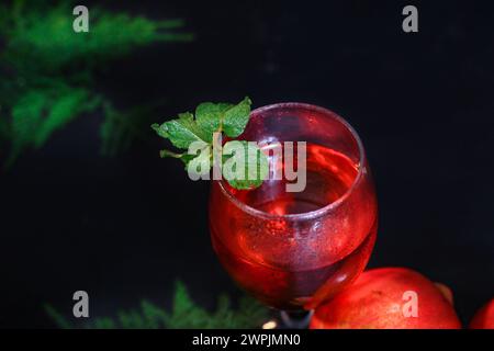 Top View of Reifen Granatapfel und Glas Wein auf schwarzem Hintergrund und mehr Blumen im besagten. Closup Stockfoto