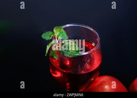 Top-Ansicht von reifem Granatapfel und Glas Wein auf schwarzem Hintergrund und mehr Minzblatt im besagten. Extreme Closup Stockfoto