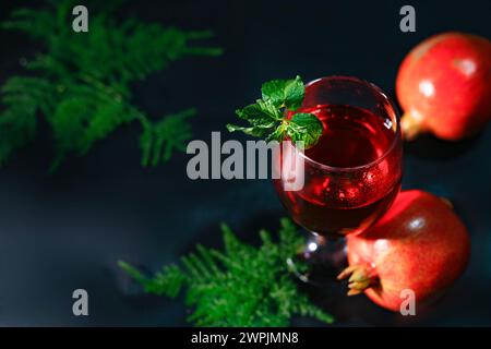 Top View of Reifen Granatapfel und Glas Wein auf schwarzem Hintergrund und mehr Blumen im besagten. Stockfoto