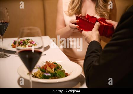 Eine Frau nimmt eine rote Box mit einem Geschenk von ihrem Gefährten an Stockfoto