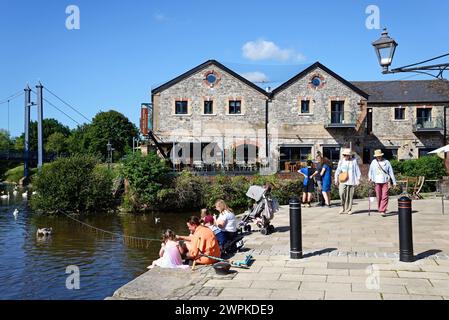 Familie, die am östlichen Kai des Flusses exe sitzt, mit einem Restaurant auf der Rückseite, Exeter, Devon, AK, Europa. Stockfoto