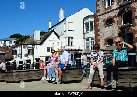 Touristen sitzen auf Bänken am Fluss exe mit dem Prospect Pub und dem Custom House auf der Rückseite, Exeter, Devon, Großbritannien, Europa. Stockfoto