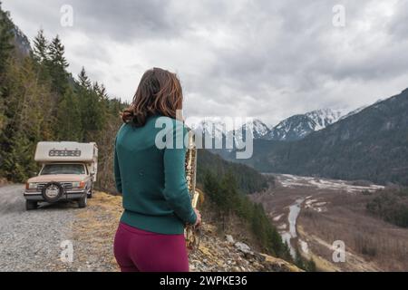 Frau spielt Saxophon neben dem Wohnmobil in den Bergen Stockfoto