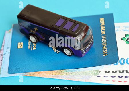 Blauer Indonesien-Pass mit Geld und Spielzeugbus auf blauem Hintergrund Nahaufnahme. Tourismus und Reisekonzept Stockfoto