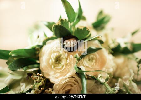 Nahaufnahme von Eheringen und Bändern an einem weißen Blumenstrauß Stockfoto