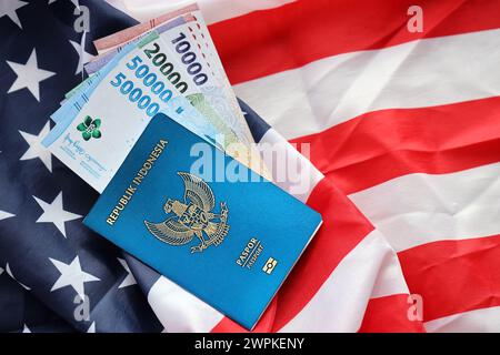 Blauer Indonesien Pass und Geld auf der US-Nationalflagge Hintergrund Nahaufnahme. Tourismus und Diplomatie Stockfoto