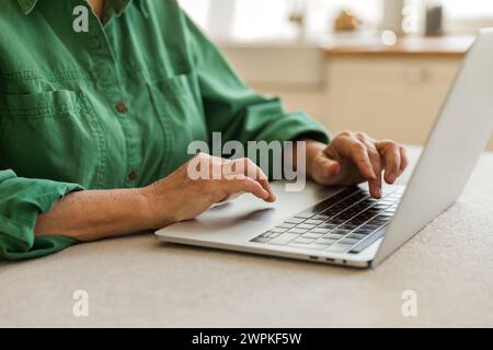 Ältere Frau, die auf der Laptop-Tastatur auf dem Tisch schreibt Stockfoto