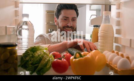 POV im Kühlschrank hungriger kaukasischer Mann Guy männlicher Koch offener Kühlschrank mit gesundem Gemüse Wahl Suche nehmen Apfel essen essen essen essen Stockfoto
